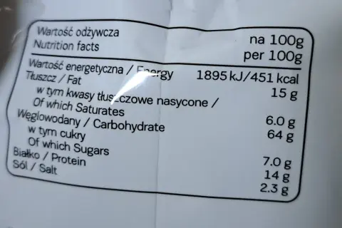 Etykieta z wartościami odżywczymi: 451 kcal na 100g. Tłuszcz 15g, węglowodany 64g, białko 7g. Idealne na 7days kcal.