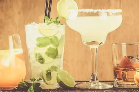 Fyra klassiska drinkar: en Mojito, en Margarita med saltkant, en orange drink och en whisky med apelsinskal.