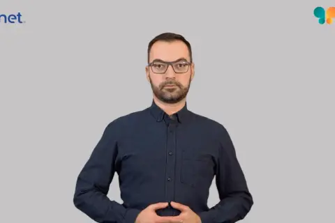 Mężczyzna w okularach i granatowej koszuli, z dłońmi złożonymi na brzuchu. Widoczne logo Euronet i Migam. Proces euronet rejestracja id.