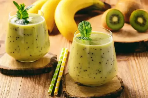 Dwa pyszne koktajle na przytycie z kiwi i bananem, ozdobione miętą. Idealne na zdrowy przyrost masy.