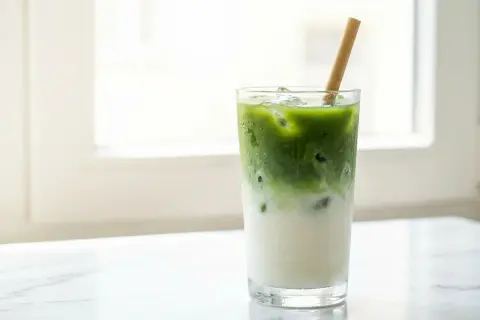 Un verre de matcha latte glacé avec une paille en bambou, parfait pour savourer son goût unique.