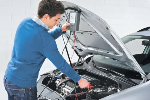 Uomo effettua manutenzione batteria auto con un tester Bosch.