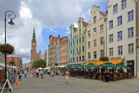Färgglada hus längs en livlig gågata på långa marknaden Gdansk. Folk promenerar och njuter av solen vid uteserveringar.