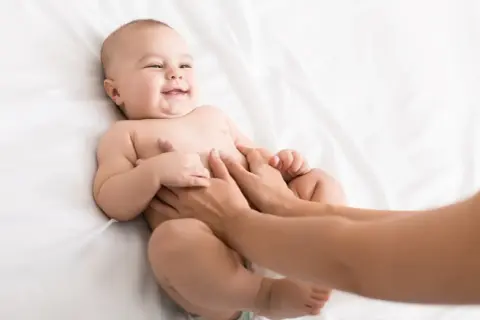 Glad bebis får magmassage på en vit bakgrund.