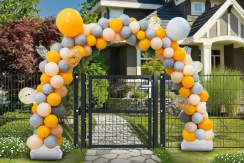 Jak samemu zrobić stojak na balony? Łuk z pomarańczowych, szarych i białych balonów nad bramką.