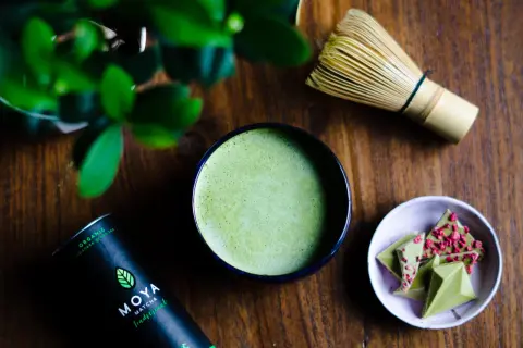 Zielone, spienione matcha w miseczce, obok bambusowa miotełka i czekoladki. To może być najdroższa herbata na świecie, przygotowana z pasją.