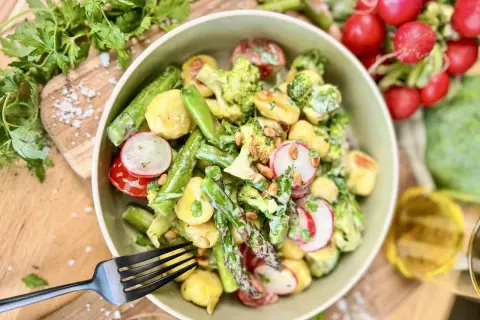 Leckerer Gnocchi Salat mit Spargel, Brokkoli, Radieschen und Pinienkernen, garniert mit frischer Petersilie.