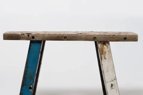 Banc rustique en bois, prêt pour une **rénovation meuble ancien**. Ses pieds bleus et blancs patinés racontent une histoire.