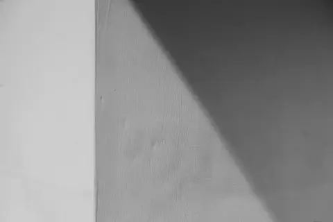 Ściana z widocznym podziałem na jaśniejszą i ciemniejszą część, o chropowatej fakturze. Wygląda jakby użyto klej zamiast tynku zewnętrznego.