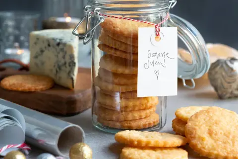 En burk med staplade parmesan kex, en bit blåmögelost och juldekorationer. Perfekt för julens fika!