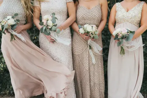 Festliche Kleider, die man zur diamantenen Hochzeit anziehen könnte: glitzernde und fließende Stoffe in zarten Farben, gehalten von eleganten Damen mit Blumensträußen.