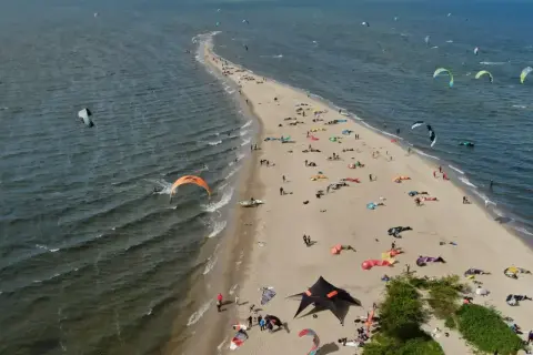 Rewa atrakcje dla dzieci: plaża pełna kolorowych latawców do kitesurfingu i ludzi odpoczywających na piasku.