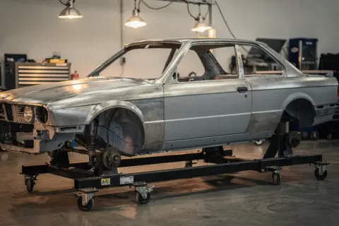 Karcass BMW E30 na wózku warsztatowym, gotowy do renowacji. Marzenie o **prawie jazdy a2** i własnym aucie zaczyna się od takich projektów.