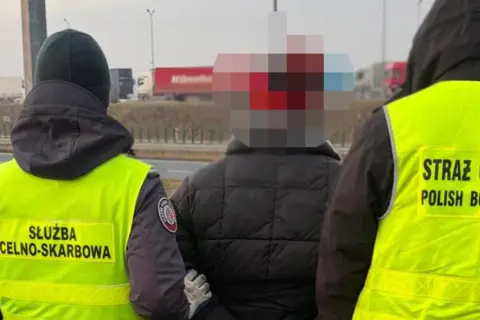 Funkcjonariusze Straży Granicznej i Służby Celno-Skarbowej zatrzymują osobę na drodze.
