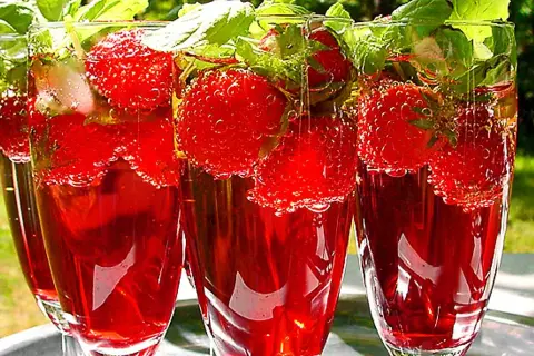 Tre glas med röd midsommar drink fyllda med jordgubbar och mynta. Perfekt för en varm sommardag.