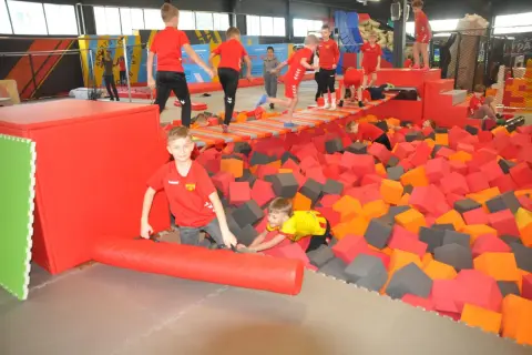 Dzieci bawią się w basenie z gąbkami w parku trampolin. To świetne kielce atrakcje dla dzieci, pełne radości i ruchu.