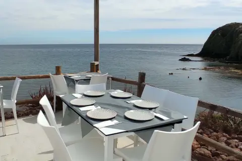 Mesas puestas en el restaurante La Isleta, listas para disfrutar de la brisa marina y un buen plato.