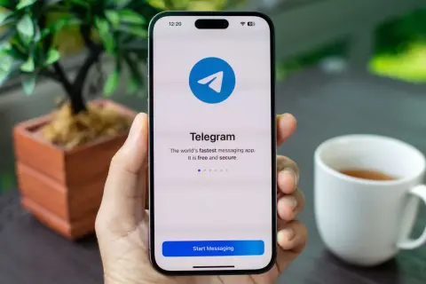 Dłoń trzyma smartfon z ekranem powitalnym aplikacji Telegram. Dowiedz się, telegram co to za szybka i bezpieczna aplikacja do komunikacji.