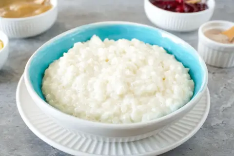 Cremiger Milchreis im blauen Schälchen, bereit für Apfelmus, Kirschen oder Zimt. Ein einfaches Milchreis Rezept für jeden Tag.