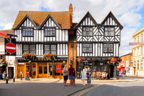 Urokliwe, zabytkowe budynki w Stratford-upon-Avon z charakterystyczną czarno-białą elewacją i kwiecistymi balkonami.