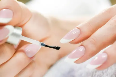 Mani curate che si preparano a fare unghie perfette con smalto trasparente.