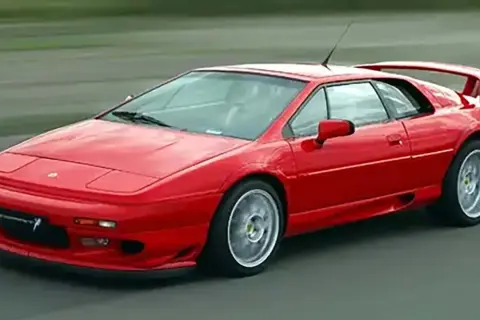 Röd Lotus Esprit, ett ikoniskt sportbilmärke, kör på en asfalterad väg.