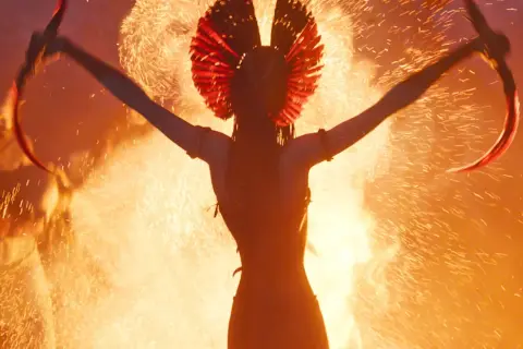 Eine Kriegerin mit rotem Kopfschmuck und gebogenen Klingen, umgeben von Feuer. Ein Vorgeschmack auf Avatar 3 stream.