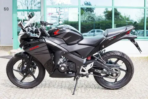 Czarny motocykl Honda CBR 125R z automatyczną skrzynią biegów, gotowy do jazdy po mieście.