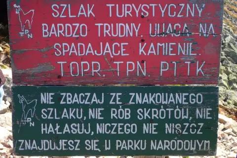 Tabliczka na szlaku turystycznym: "Bardzo trudny, uwaga na spadające kamienie". Niżej: "Nie zbaczaj ze szlaku, nie rób skrótów, nie hałasuj, niczego nie niszcz. Znajdujesz się w Parku Narodowym". Przełęcz Karb.