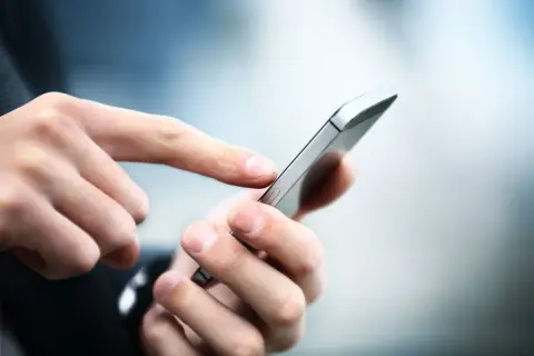 Dłoń z palcem wskazującym dotyka ekranu smartfona, korzystając z aplikacji Citi Handlowy.