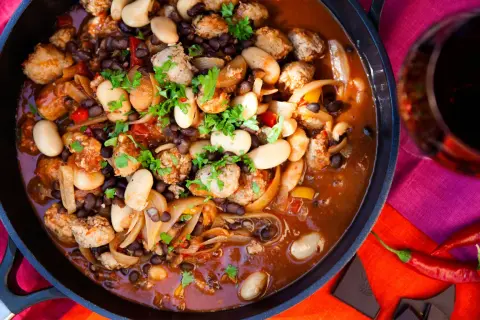 En mustig korvgryta med bönor och lök, perfekt för ett mysigt middagsrecept. Serveras med rödvin och chili.