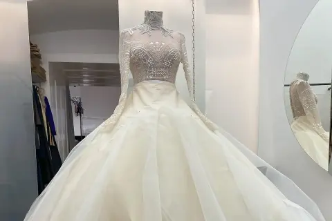 Ein prachtvolles, elfenbeinfarbenes Brautkleid mit einem hochgeschlossenen, bestickten Oberteil und einem voluminösen Tüllrock. Dieses Kleid könnte das Hochzeitskleid einer Kaiserin sein.