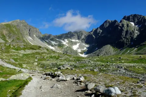 Kamienista ścieżka prowadzi przez zieloną dolinę w Tatrach Słowackich. Idealne tatry słowackie szlaki dla średnio zaawansowanych, z widokiem na skaliste szczyty.