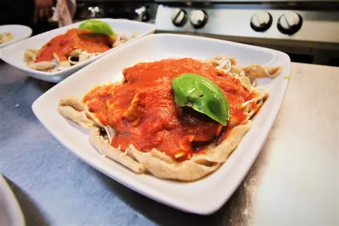 Sagne torte fatte in casa con sugo di pomodoro fresco e basilico, servite in un piatto bianco.