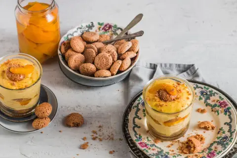 Delizioso tiramisù alle pesche in bicchiere, con amaretti e pesche sciroppate.