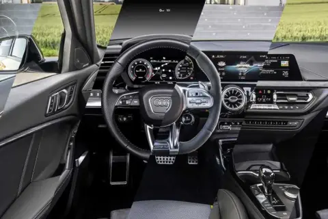 Interni moderni dell'Audi A3: volante sportivo, cruscotto digitale e console centrale con cambio automatico.