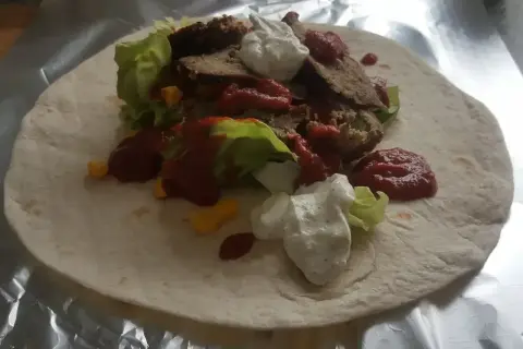 Domowy kebab z baraniną, sałatą, kukurydzą, sosem pomidorowym i jogurtowym na tortilli.
