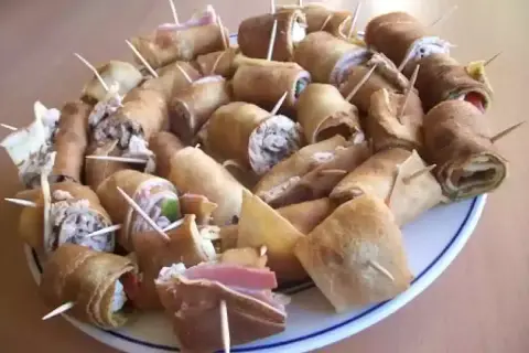 Assiette de crêpes roulées garnies, parfaites pour un apéro convivial. Des bouchées savoureuses prêtes à être dégustées.