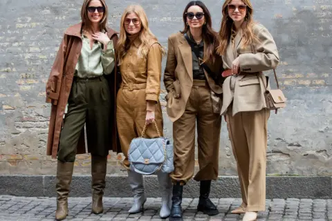 Vier Frauen in erdigen Tönen zeigen, was man bei 10 Grad anzieht: Leder-Trenchcoat, Anzüge und Stiefel.