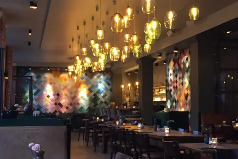 Mysig restaurang i Berlin med många vackra lampor och en färgglad vägg. Perfekt för en middag på en av Berlins bra restauranger.