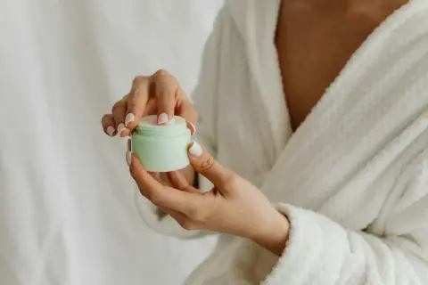 Hände mit gepflegten Nägeln öffnen eine Creme. Die positive resveratrol wirkung haut wird durch diese Pflege unterstützt.