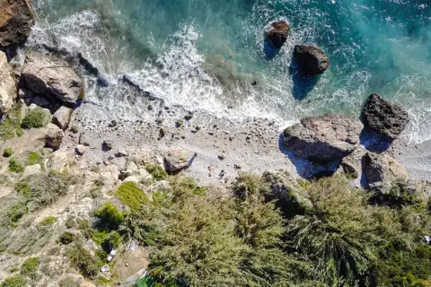 Vista aérea de la cala Barranco de Maro, con rocas, vegetación y el mar turquesa.