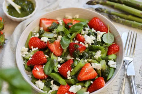 Frischer Spargelsalat mit Erdbeeren, Feta und Basilikum, beträufelt mit Pesto. Ein leichter Genuss für den Frühling.