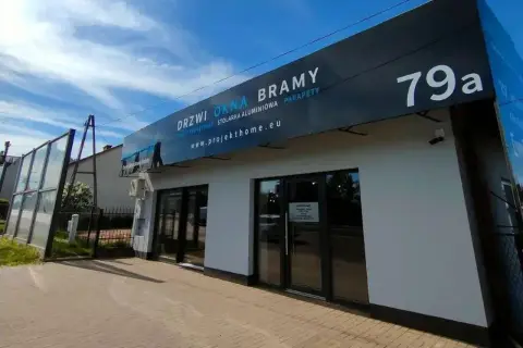 Nowoczesny salon okien i drzwi z szyldem "DRZWI OKNA BRAMY" i numerem 79a.