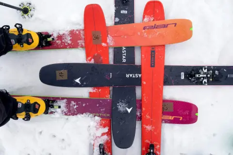 Skier mit gelben Tourenschuhen und Skiern in verschiedenen Farben, darunter ein schwarzer Ski mit der Aufschrift "black crows navis freebird".