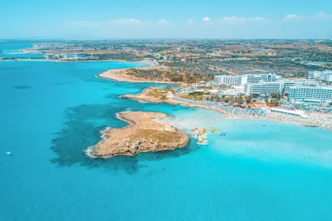 En livlig strand med turkost vatten, solbadande och vattensporter. Perfekt för Ayia Napa aktiviteter.