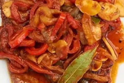 Ein saftiges Paprikaschnitzel-Rezept mit geschmortem Paprika, Zwiebeln und Pilzen, garniert mit einem Lorbeerblatt.