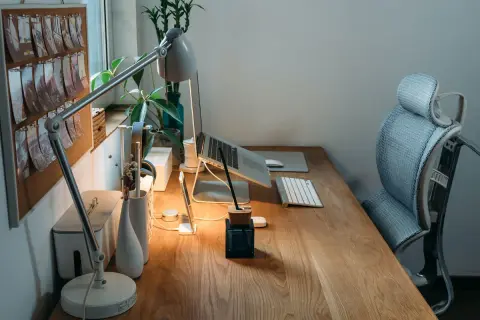 Bureau en bois avec plan de travail, ordinateur portable, lampe, clavier et chaise ergonomique. Une idée d'espace de travail fonctionnel et esthétique.