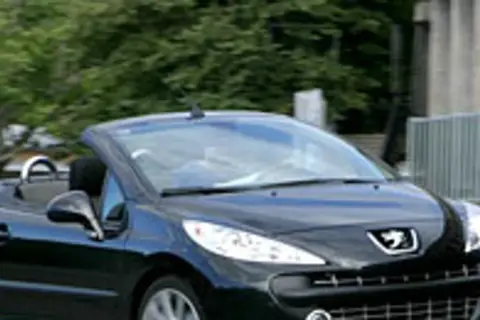 Czarny kabriolet Peugeot 207 CC z opuszczonym dachem jedzie po drodze.