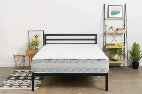A white and gray mattress on a black metal bed frame. This is one of the mattresses to avoid if you want a good night's sleep.